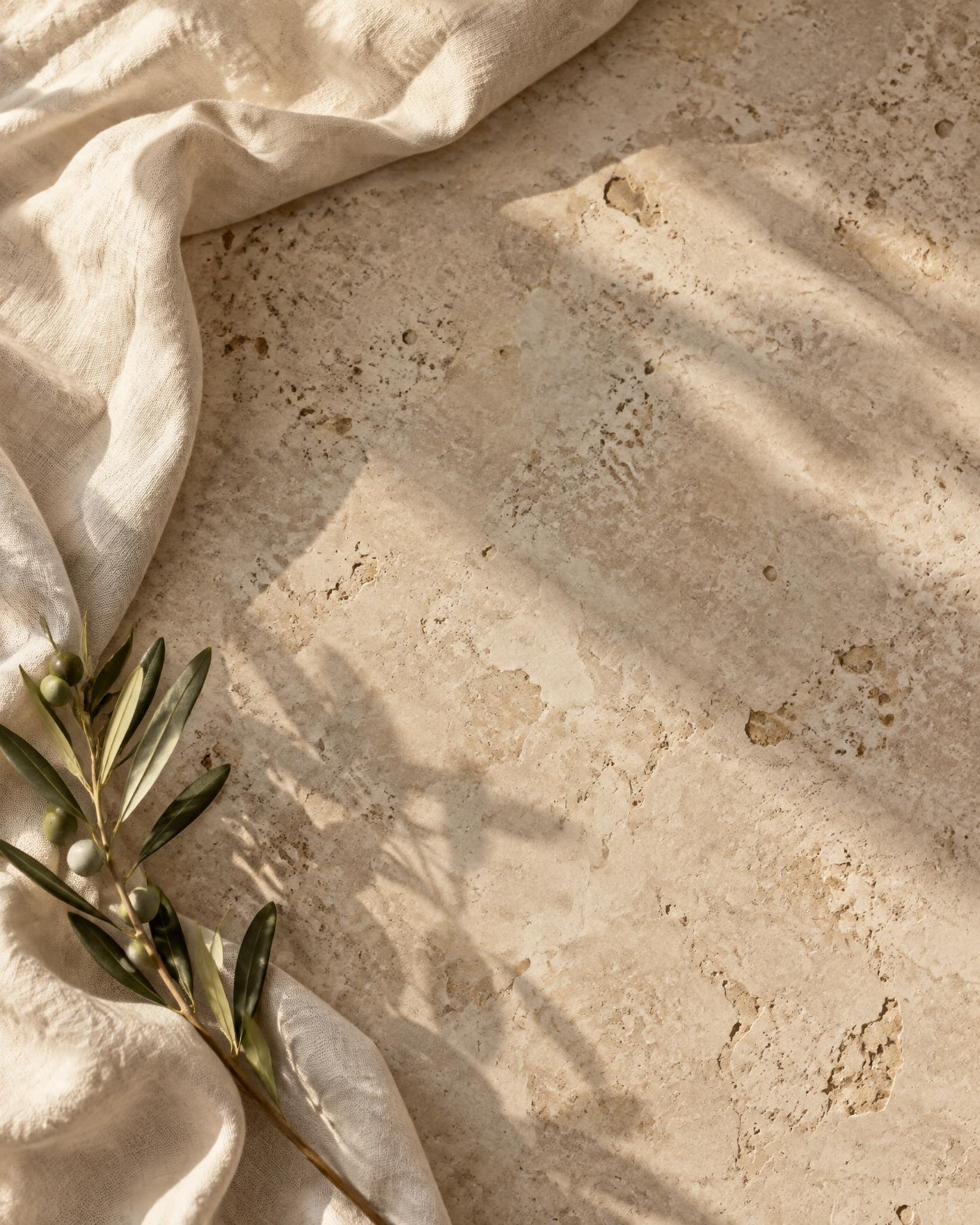 Travertine stone and ivory linen surface with an olive branch